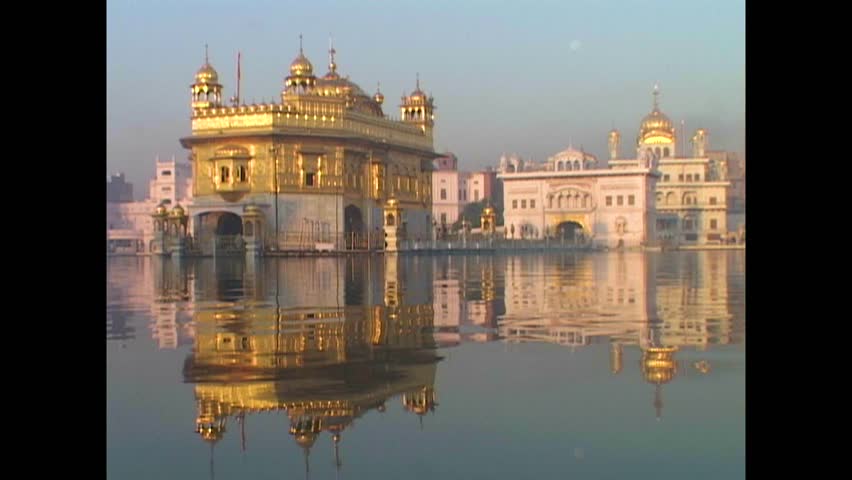 INDIA - 1999 - India's Golden Temple is reflected in the sacred pool it stands above at dusk. Royalty-Free Stock Footage #3460597733