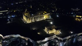 Aerial birds eye view night video taken by drone of iconic Acropolis hill and the Parthenon, Athens historic center, Attica, Greece