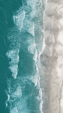 Vertical video of Drone aerial view of paradise beach. Turquoise sea water and clear sand at sunset.