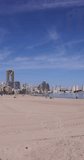 Portrait footage of the town of Benidorm in Spain in the summer time showing high rise apartments and building along side the West Beach Promenade long beach on a sunny day