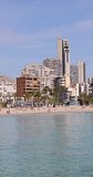 Portrait footage of the town of Benidorm in Spain in the summer time showing the beach known locally as Playa de Finestrat and hotels and apartments around the small beach in the summer time