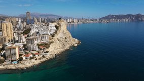 Aerial drone footage of the town of Benidorm in Spain in the summer time showing high rise apartments and building along side the West Beach Promenade long beach