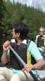 Senior couple canoeing on a forest lake in Finland. Active retirees enjoy outdoor sports. Sportive elderly people having fun at the nature. A vertically-oriented video.