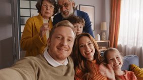First person view on big caucasian family waving hello to camera during video call at cozy apartment interior. Friendly people communicating with long distance relative and making greeting gesture. - Powered by Shutterstock - Get 15% off with code: PIKWIZARD15