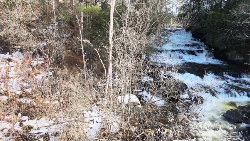 Waterfall flowing aerial view while panning to the right in Paradox NY