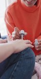 Vertical video of happy diverse teenager girls painting nails at home, slow motion. Spending quality time at home, domestic life and friends concept.