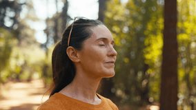 Peaceful senior retired woman relaxing standing amongst nature in forest surrounded by trees with closed eyes breathing deeply - shot in slow motion - Powered by Shutterstock - Get 15% off with code: PIKWIZARD15