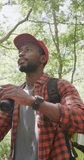 Vertical video of african american man using binoculars in park, slow motion. Nature, hiking and park concept.