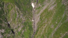 Valea rea in the fagaras mountains with rugged terrain and trails, during daylight, aerial view