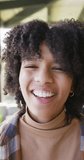 Vertical video of portrait of happy african american teenager girl at home, slow motion. Spending quality time at home, domestic life and friends concept.