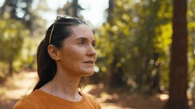 Peaceful senior retired woman relaxing standing amongst nature in forest surrounded by trees with closed eyes breathing deeply - shot in slow motion - Powered by Shutterstock - Get 15% off with code: PIKWIZARD15
