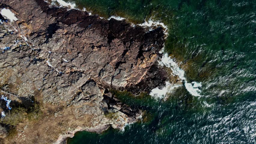 Large rocks on the shores of the North Shore coast where the waves break. Aeria view.