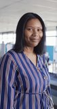 Vertical video of portrait of african american businesswoman smiling, slow motion. Working at office, business concept.