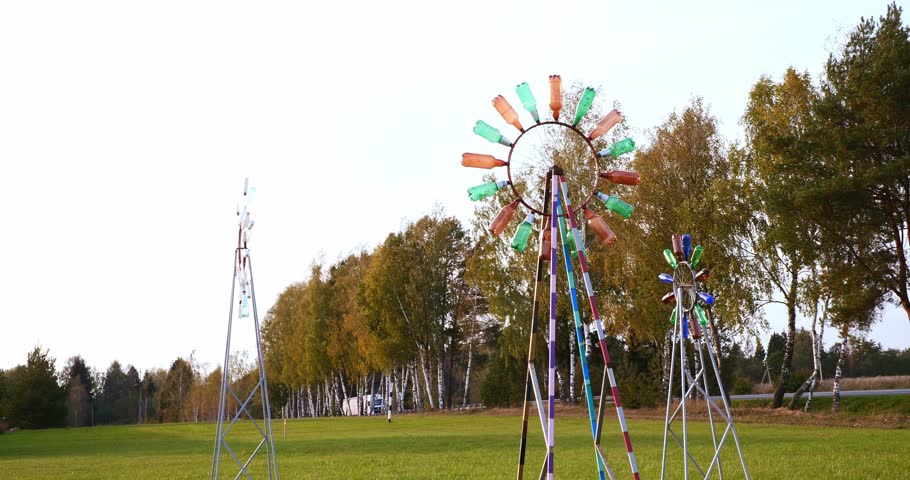A wind wheel made from old plastic bottles stands on a green lawn and shows the strength of the wind. Using old plastic bottles for household needs. Demonstration of plastic recycling.