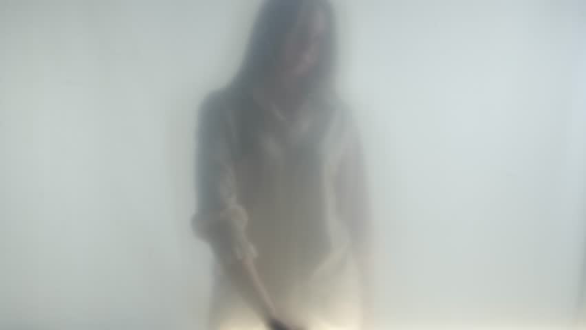 Silhouette of ghost woman in fog behind frosted curtain or glass close up. A woman is touching the glass. Concept of afterlife, otherworld, ghosts. Royalty-Free Stock Footage #3460949291