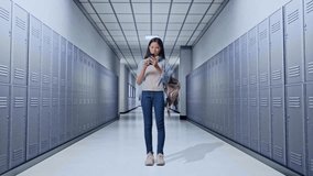 Full Body Of Asian Teen Girl Student With A Backpack And Some Books Having A Video Call On Smartphone While Standing in Corridor