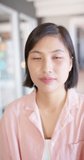 Vertical video portrait of asian businesswoman opening eyes and smiling in office, slow motion. Business, work and communication concept.