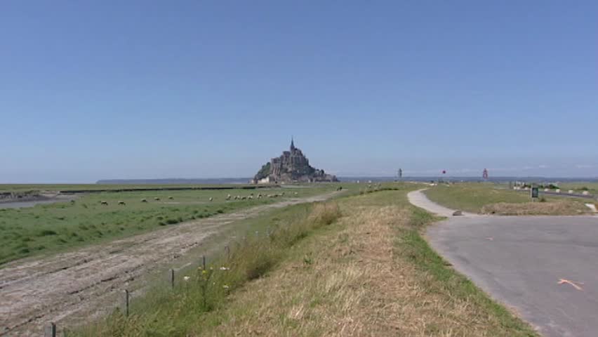 Le Mont Saint-Michel in bay behind marshes + zoom in. On the barren rock, monks founded an abbey in 966. Mont Saint-Michel and its bay are part of the UNESCO list of World Heritage Sites