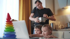 father cooking in kitchen remote work. baby twins playing with laptop in the kitchen lifestyle. father working at home in the kitchen stirring food in the pan. remote work business concept - Powered by Shutterstock - Get 15% off with code: PIKWIZARD15