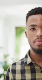 Vertical video of happy african american man looking into camera. Lifestyle, spending free time at home concept.