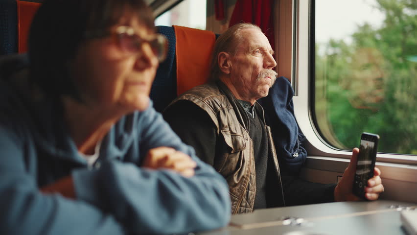 An elderly couple travels by train, Slow motion. An old husband and wife are traveling on a train.