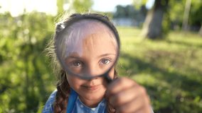 the girl holds magnifying glass in her hands. gaining knowledge and curiosity concept. a schoolgirl girl with a black magnifying glass is examining lifestyle something, park on the background - Powered by Shutterstock - Get 15% off with code: PIKWIZARD15
