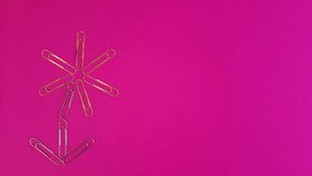 Paper clips stop motion. Metal paper clips appear on a pink background in the shape of a flower.