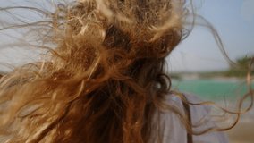 Healthy long hair blowing in wind. Pretty curly model with airy, strong hair posing at coast, sea surf. Young caucasian woman with natural, shiny hair enjoy sunny day at the ocean shore. Close-up. - Powered by Shutterstock - Get 15% off with code: PIKWIZARD15
