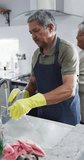 Vertical video of happy senior biracial couple washing dishes. Spending quality time at home, retirement and lifestyle concept.