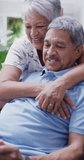 Vertical video of happy senior biracial couple embracing. Spending quality time at home, retirement and lifestyle concept.