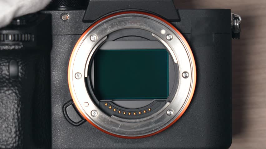 Removing sensor dust from a modern digital mirrorless  full frame camera sensor using a sensor swab – top view close up Royalty-Free Stock Footage #3461317519