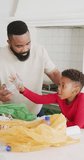 Vertical video of african american father and son sorting waste in kitchen, in slow motion. Spending quality time, domestic life and childhood concept.