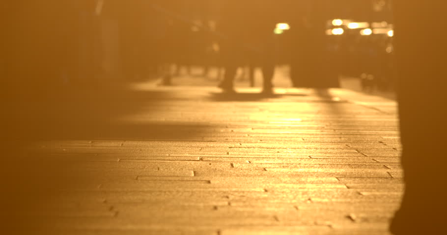 People are walking, background. Silhouettes of pedestrians legs steps move along sunlit sidewalk, embodying everyday life and reflecting people's daily actions amidst an atmosphere of warmth and light Royalty-Free Stock Footage #3461342409