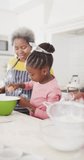 Vertical video of happy african american grandparents and grandchildren cooking at home, slow motion. Happiness, family, togetherness and domestic life concept.