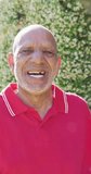 Vertical video portrait of happy senior biracial man laughing in garden, in slow motion. Healthy, active senior lifestyle.