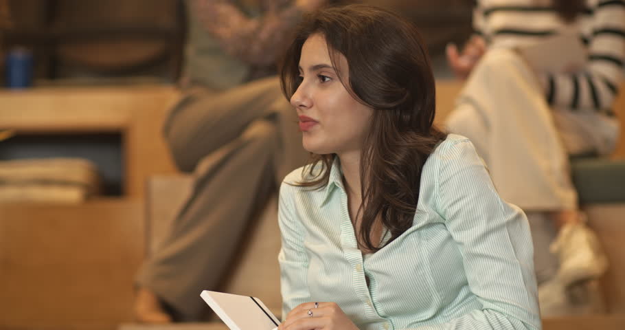 In an amphitheater room during a business seminar, a group of international and multiracial people engage in discussions and interactions.