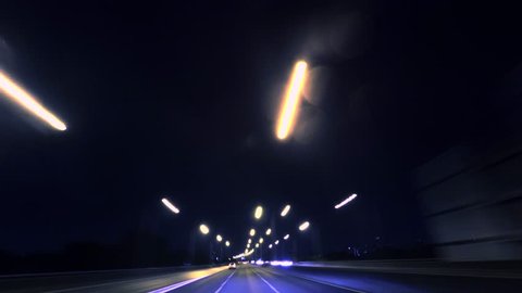 4K Timelapse - Long exposure shot of car moving on urban road at night. Camera placed on vehicle roof. (POV #5)