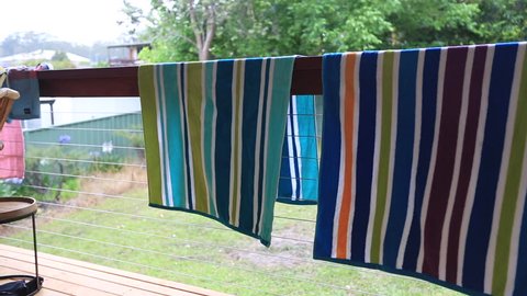 Colourful of beach towel drying on the wood bench at the back of the house 