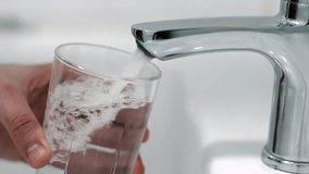 A man pours tap water into a glass glass. The concept of clean drinking water in a centralized water supply system. - Powered by Shutterstock - Get 15% off with code: PIKWIZARD15