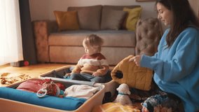 Mom and a kid pack luggage together. Asian mother and her toddler son preparing for their travel adventure, packing clothes into suitcase, getting ready for road trip travelling, happy family concept. - Powered by Shutterstock - Get 15% off with code: PIKWIZARD15