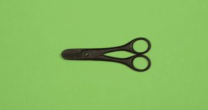 Vintage black scissors in action on green color background. DIY video concept. Top view, 4K stop motion animation loop.