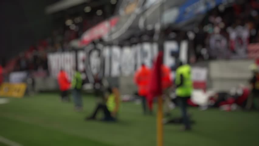 a blurred spot, a football match in sunny weather, the stands at stadiums are filled with people, fans celebrate the victory of their team, football fans burn fire, fans wave team flags