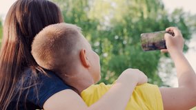 Selfie of children on phone. Sending photos to social networks. Teenagers are photographed using smartphone in park. Group of young teenage girl and boy who are talking via video link using smartphone