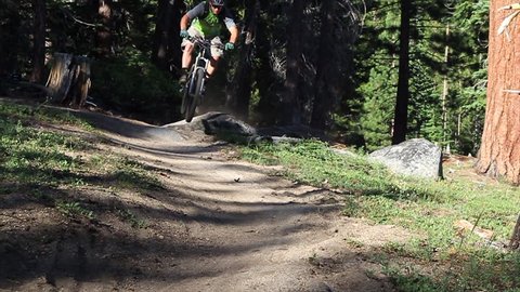 An extreme mountain biker speeds down a bike trail in the forest during the day Stock Video