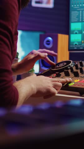 Vertical Video Experienced audio engineer uses mixing board to create new song in recording home studio. Post production equipment and tools on computer, operates digital audio workstation software Royalty-Free Stock Footage #3461961699