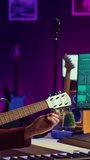 Vertical Video Musician trying to tune the sound of his guitar in home studio, adjusting knobs before playing tunes and recording on daw software. Advanced mixing and mastering techniques. Camera A.
