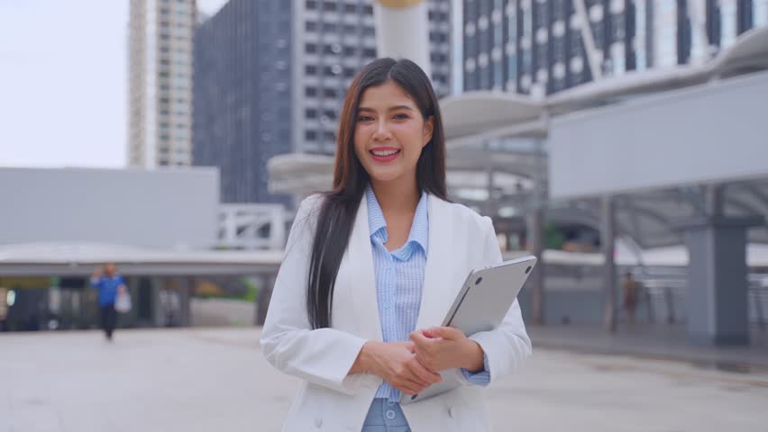 Portrait of Asian youg beautiful businesswoman standing outdoor in city. Attractive employee girl worker feel happy and confident then smile, looking at camera. Job application and recruitment concept