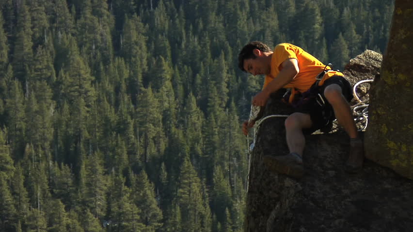 A male climber throws a safety rope across a gorge
