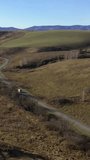 Vertical drone video of flying over a hilly rural landscape with a winding road and fish ponds in Altai Krai.