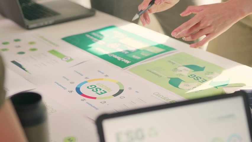 A team engages in a detailed discussion over documents related to ESG targets, circular economy, and sustainability strategies.